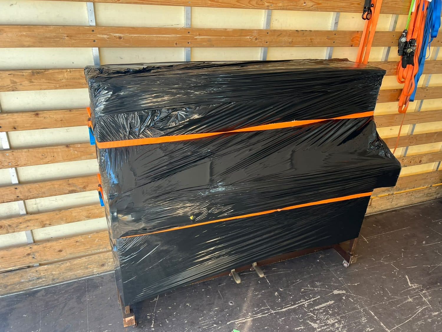 Piano ingepakt in beschermfolie en vastgezet met spanbanden